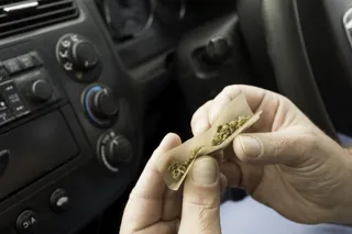 Person rolling a joint in a car