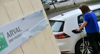 Arval sign with woman plugging a VW Golf into an electric charging point