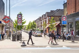Pedestrians cross the road outside Tooting Bec station with 20mph speed limit 