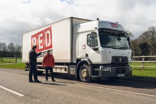 Red Corporate Driver Training instructor with driver in front of truck